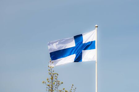 Finnish national flag on the wind against the blue skyの写真素材