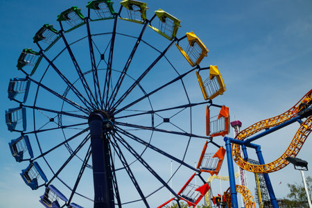 Colorful rides in motion in amusement park on sky background.