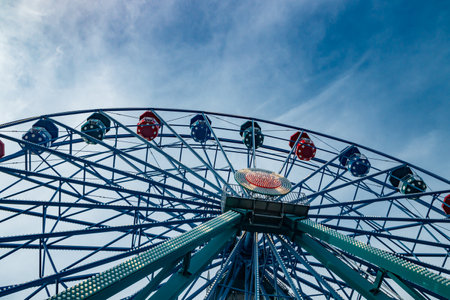 Colorful ride ferris wheel in motion in amusement park on sky background.