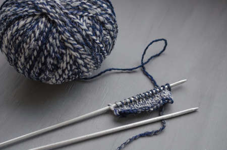 Woolen melange yarn and knitted pattern on knitting needles on a gray backgroundの写真素材