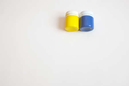 A set of gouache paints - blue and yellow on a light background. closed jars. Free space for text. close-up.の写真素材