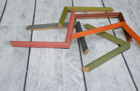 Samples of decorative wooden picture frames. Multi-colored frames for a baguette, randomly lying on...