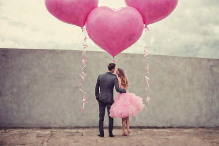 A couple of lovers - a girl in a lush pink dress and a young man in a suit with pink balloons with hearts. Valentine's Day.の素材