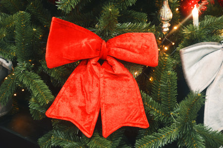 A large beautiful red bow on the branches of a Christmas tree. Beautiful holiday decoration.の写真素材