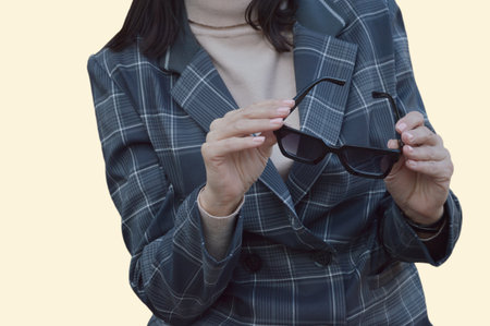 A brunette business woman in a gray suit holds sunglasses in her hands.の写真素材