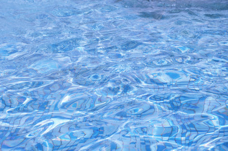 Abstract background of blue water glare on the surface in a pool, fountain on a sunny day.
