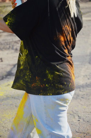 Detail of a black T-shirt and white pants with bright abstract spots of yellow orange paint. Street festival of colors.の写真素材