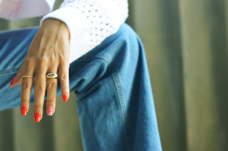 Female hand with bright red summer manicure on denim background.