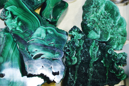 Several uncut green malachite stones lie on a table. These are semi-precious natural stones and...