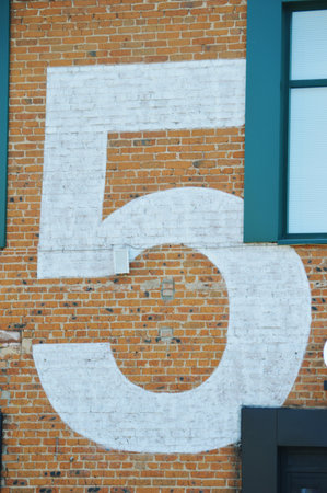 A large number five painted in white on a red brick wallの写真素材