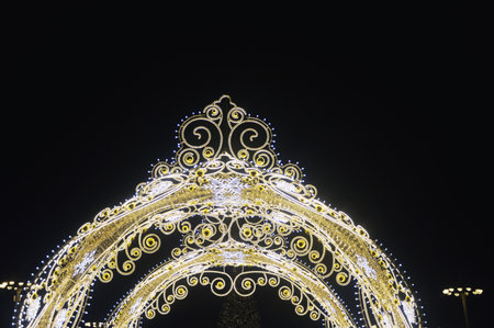 A fragment of Christmas street decorations, golden garlands and festive illuminations against the night sky.の写真素材