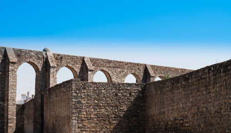 Wide angle view of the Roman aqueduct at Evora, Portugal, with a clear blue sky overhead.の写真素材