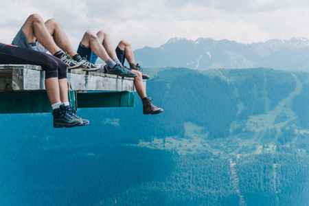 Legs of hikers of beautiful mountains view and green meadows, tourists legs in trekking shoes chilling on the air copy spaceの写真素材