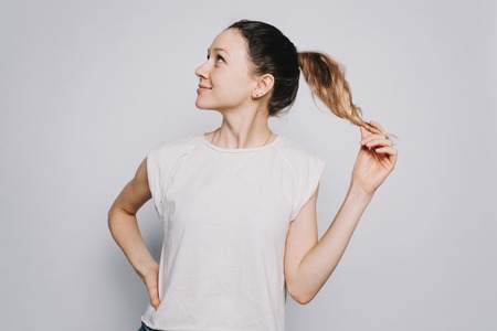 young happy girl in white t-shirt with a ponytail in profile looking in expectation of a joyful momentの写真素材