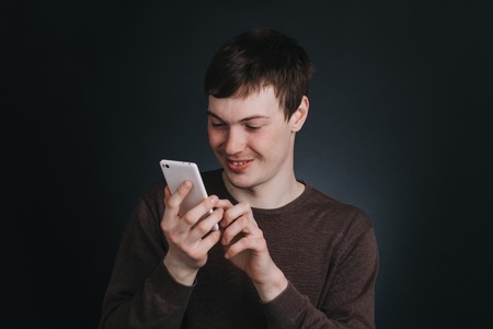 A man looks at a mobile phone screen and dials the message , the portrait of a man close up in...