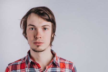 Portrait of a man in a plaid shirt on a white background close-up, a man without emotions, copy space - isolatedの写真素材