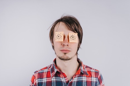 Stickers with painted eyes are glued on mans eyelids, isolated white background