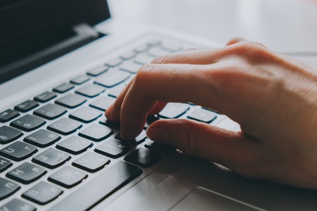 Working at home with laptop woman typing on a keyboard