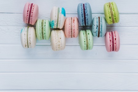 Macaron or macaroons or almond cookies lie on a wooden white background. Top view close-up, copy space.の写真素材