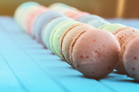 Line of multicolored macaron or macaroons on a turquoise wooden background, almond cookies in pastel tones, selective focus, toning.の写真素材