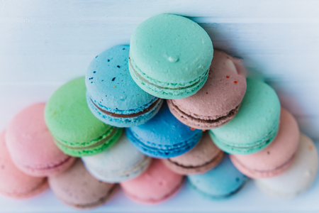 Pyramid of multicolored macaroons on a white wooden background, almond cookies in pastel tones. Top viewの写真素材