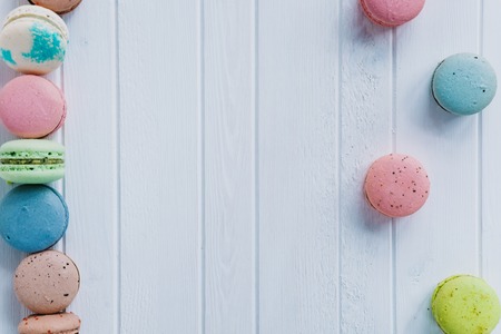 Multicolored macaroons or macaron on a white wooden background, copy spaceの写真素材