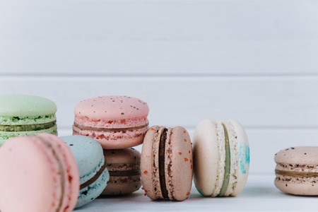 Delicious macaroons or macaron on a white wooden background close-up. Almond cookies on a table, copy spaceの写真素材