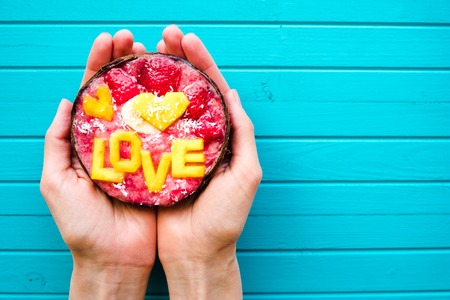 Smoothie bowl in female hands on a turquoise wooden background, copy space. Concept of diet, proper...