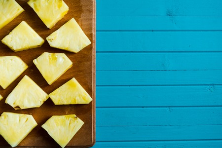 Pieces of pineapple on a cutting board, top view. Fruit summer concept, copy spaceの写真素材