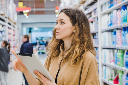 Young business woman with a tablet picks a product in a supermarketの写真素材