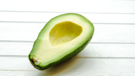 Ripe avocado on a white wooden background