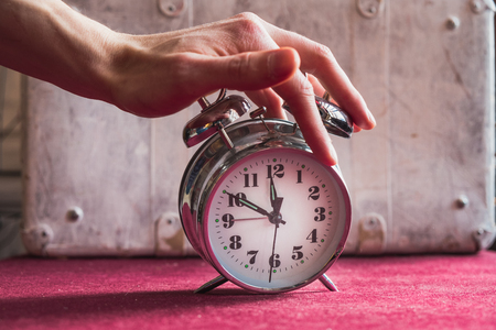Hand man turns off the alarm clock, awakening from sleepの写真素材