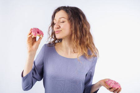 Young woman with relish eating a donut. The concept of harmful nutritionの写真素材