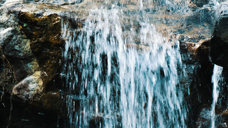 Mountain stream flows down from the stone, a small waterfall and splashes