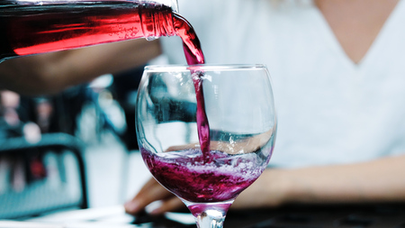Woman pours soda lemonade from a bottle in a restaurant in a glass, close-up.の写真素材