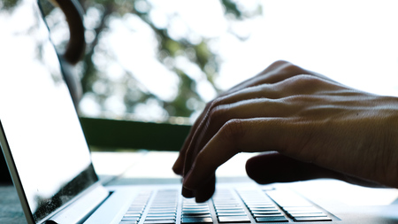 Close-up woman typing on a laptop outdoors in summer by natureの写真素材