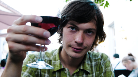 Man on a date clinks a glass of wine with a girl and takes a sip in a restaurant, close-up.の写真素材
