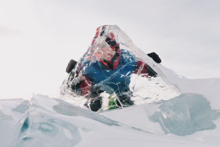 A man looks through a transparent ice on Lake Baikalの写真素材