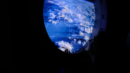Woman looks out into the porthole in spaceの写真素材