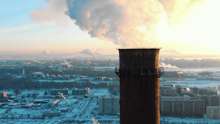 Aerial view of smoking chimneys in a residential area of the city at sunset in winterの写真素材