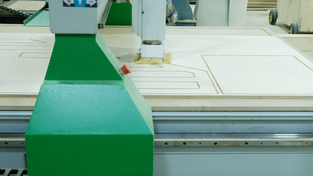 Modern woodworking machine in action. Cuts curly pieces from plywood sheet. Production of wooden...