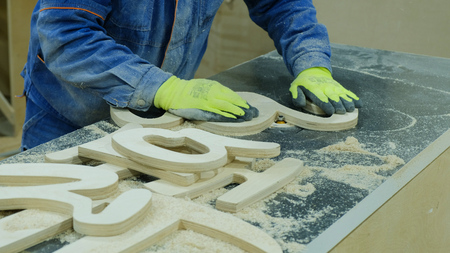 A man removes a chamfer with a radius cutter at a furniture factory. Manufacture of wooden furnitureの写真素材