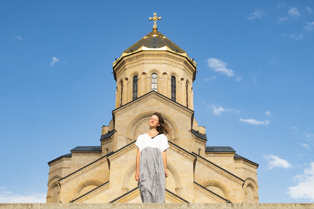 Portrait of a young beautiful girl against the background of Tsminda Sameba, an ancient Christian Church in Georgia.の写真素材