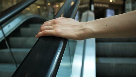 Girls hand on escalator handrail in mall, close-upの写真素材