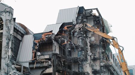 Destruction of the house with a bulldozer. Dismantling the old building. Excavator destroys the walls of an abandoned houseの写真素材