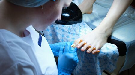 Pedicurist paints toenails at the client in the beauty parlor