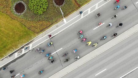 flying camera shows different cyclists in colorful jackets riding along new asphalt road past...