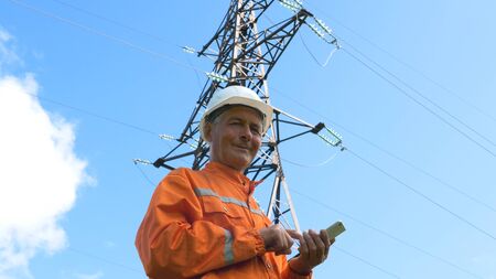 surveyor in jumpsuit and helmet smiles holding smartphone