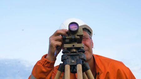 concentrated surveyor looks through theodolite and writesの写真素材