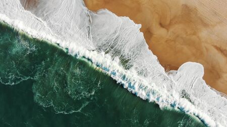 attractive upper view of turquoise ocean washing golden sand beach with powerful foamy waves at sunshineの写真素材